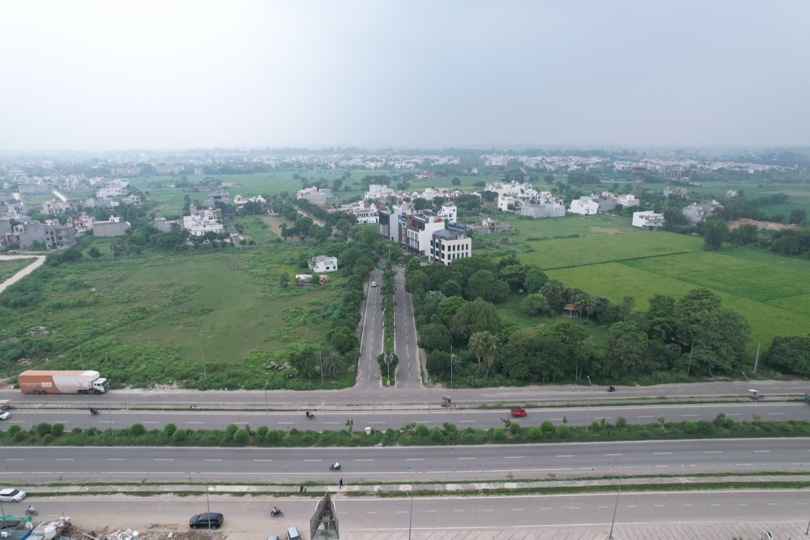 Aerial view of Veer Enclave from the highway, its avenue running back between plots and completed houses