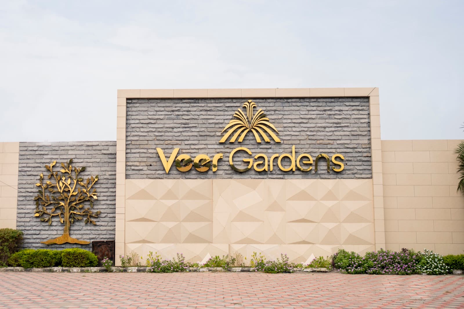 The Veer Gardens entrance wall, gold lettering and a metal tree relief set into stone